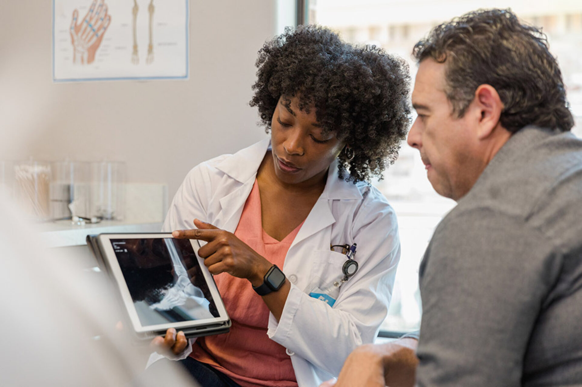 Médica mostra exame ao paciente durante consulta sobre cirurgia e cobertura do plano de saúde
